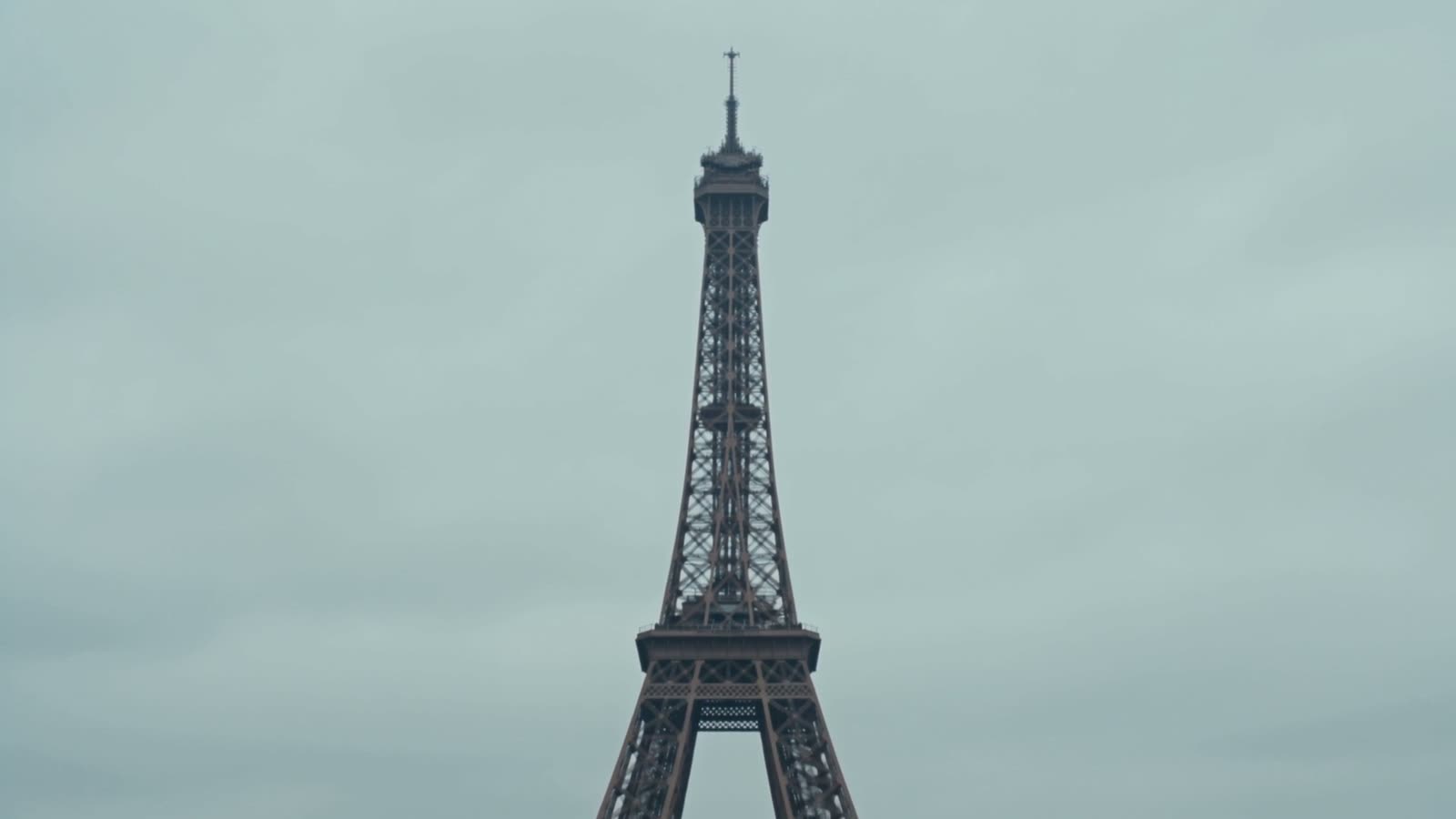 The tower today against a grey sky, seen across Paris rooftops
