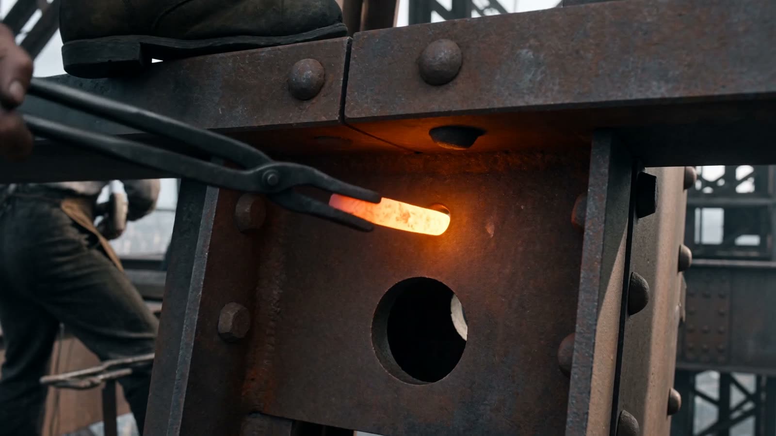 A glowing rivet held in tongs against cold riveted iron